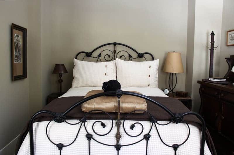 A bedroom with a wrought iron bed and two lamps