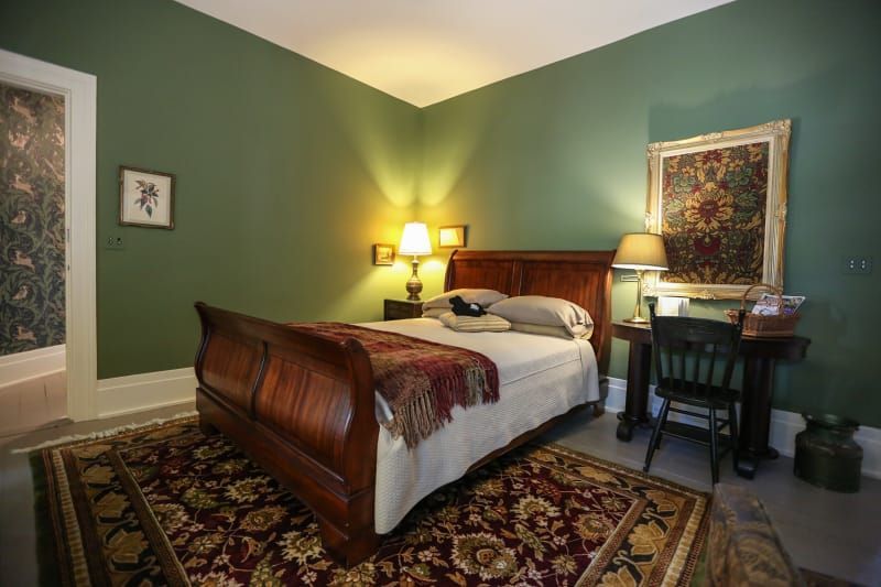 A bedroom with green walls and a sleigh bed