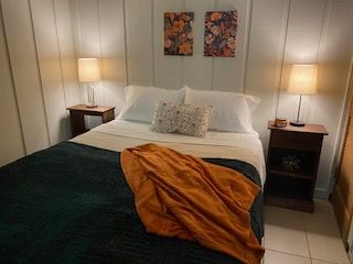 Cozy bedroom with a neatly made bed, bedside lamps, and a mustard throw blanket.