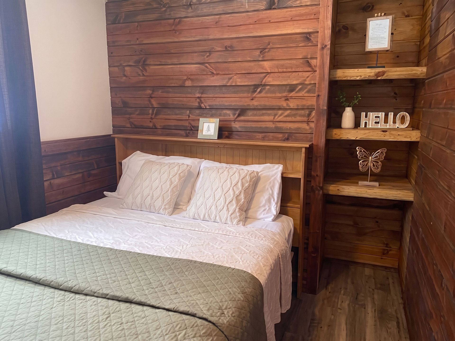 Cozy bedroom with a bed, green blanket, and rustic wood headboard and shelves