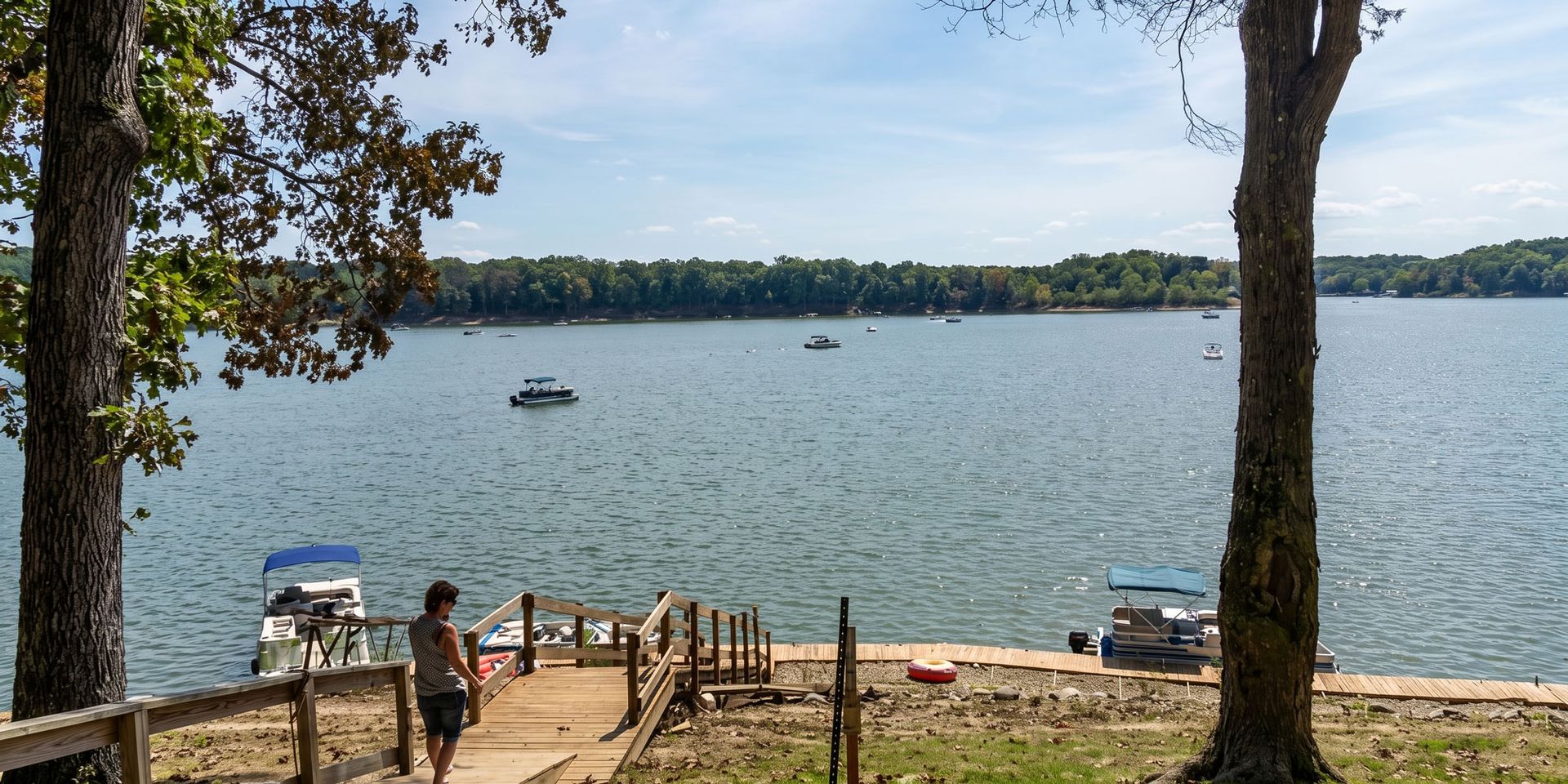 Lake view from a dock with trees, a bench, and a small boat on calm water