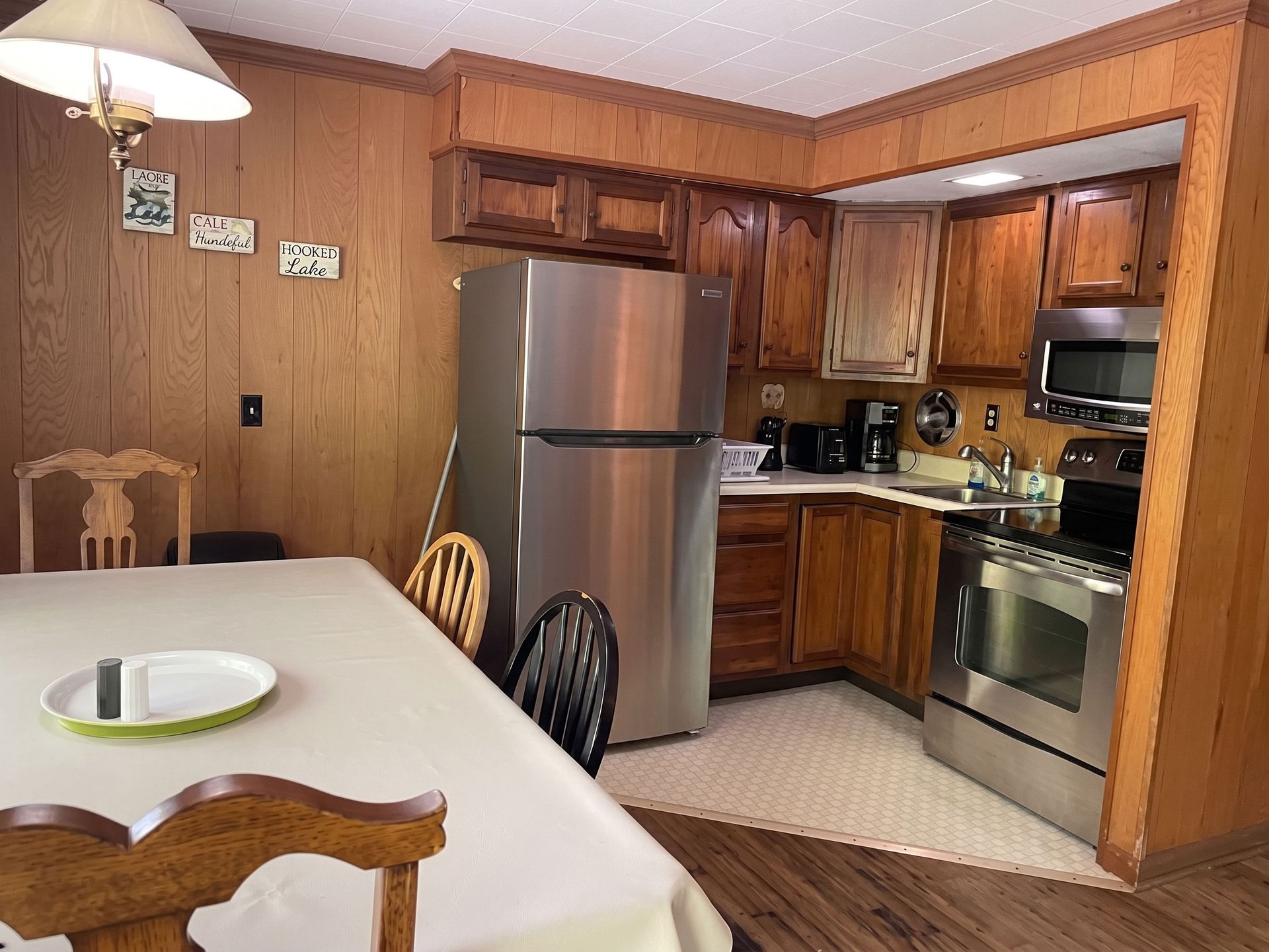 Wood-paneled kitchen with stainless steel appliances and a white dining table in the foreground