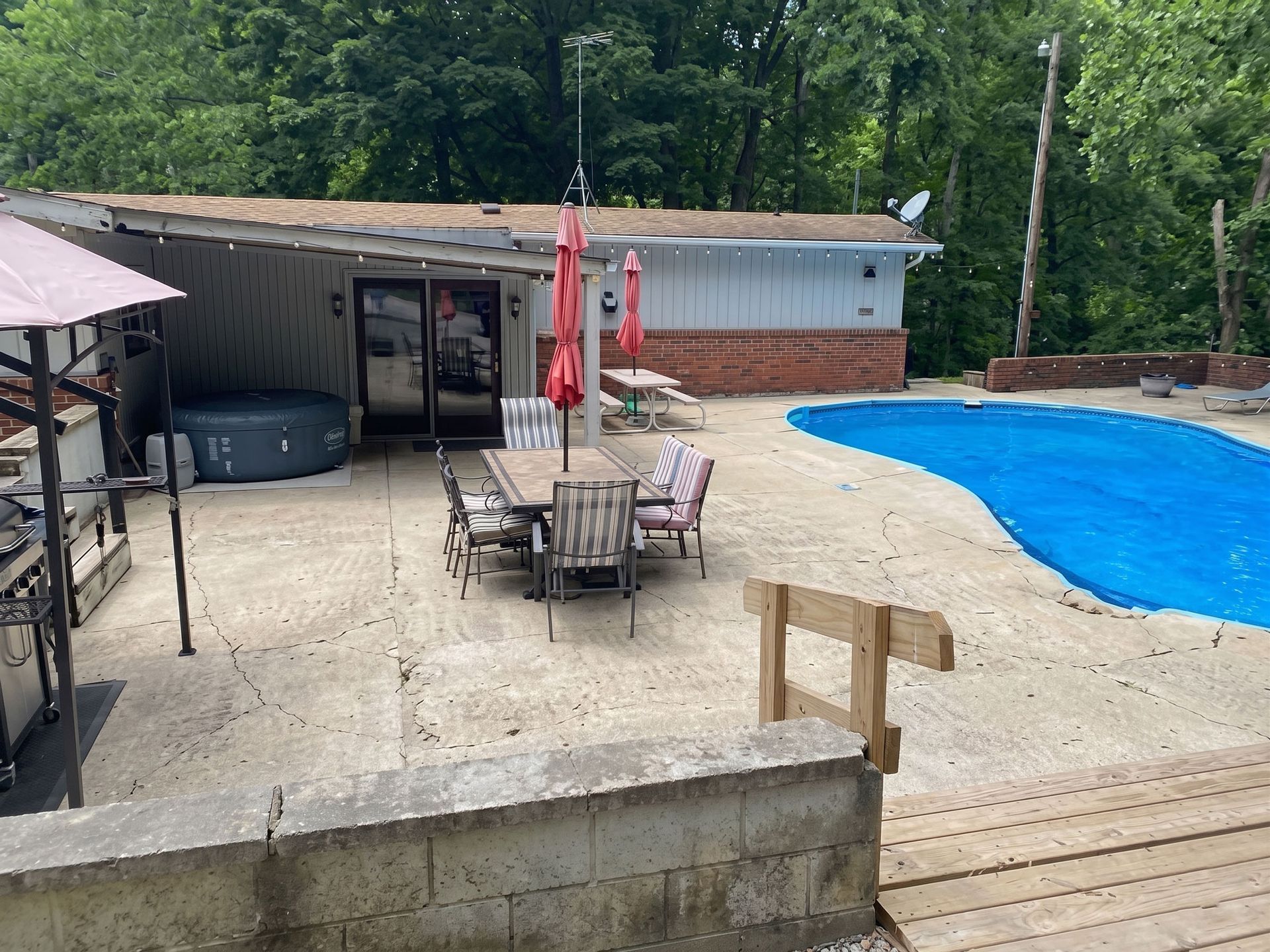 Backyard pool deck with patio table, red umbrella, shed, and covered pool