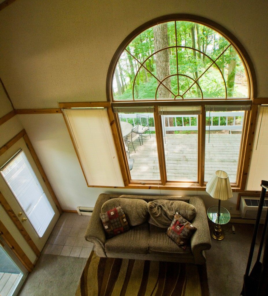 Living room with a large arched window, beige sofa, lamp, and sunlight streaming in