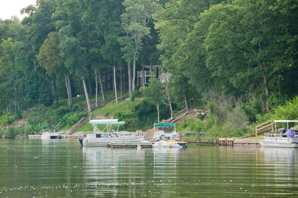 Small boats moored by a calm riverbank with dense green trees and reflections on the water