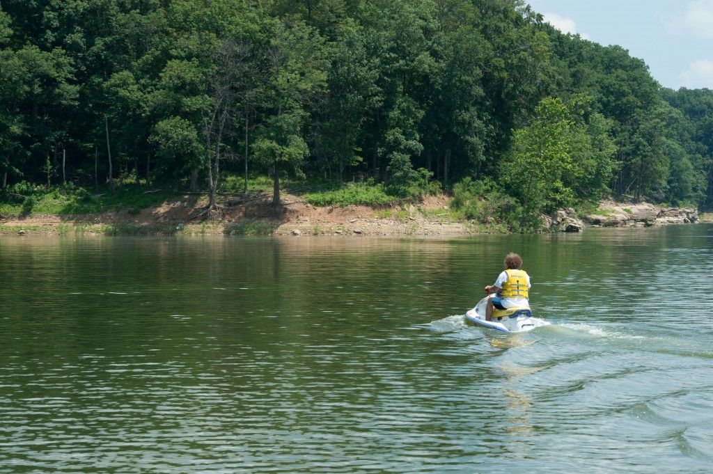 Person kayaking on a calm river near a wooded shoreline