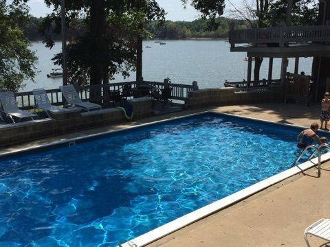 Outdoor swimming pool beside a lake with lounge chairs and two people relaxing by the water