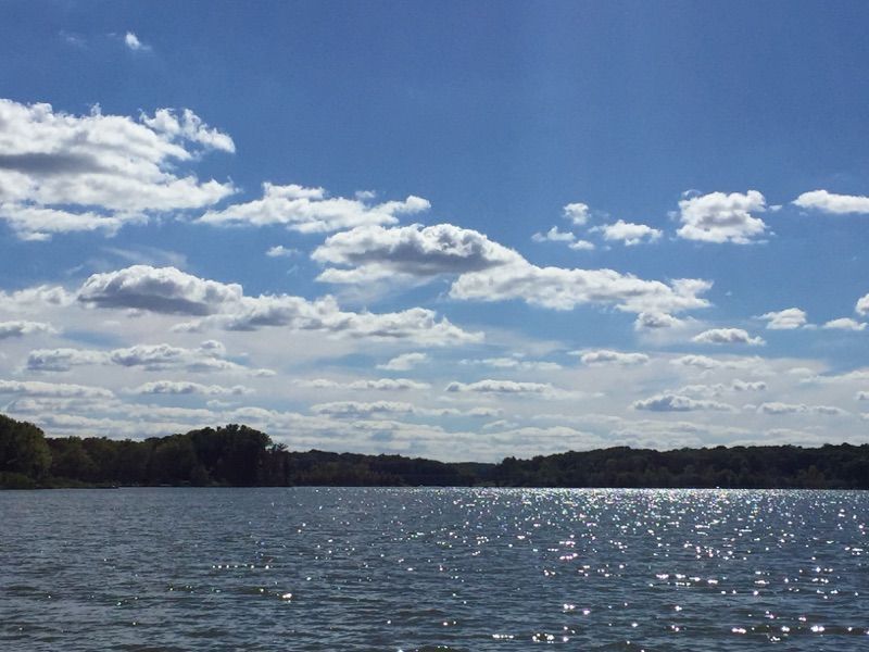 Lake with sparkling water under a blue sky filled with scattered clouds