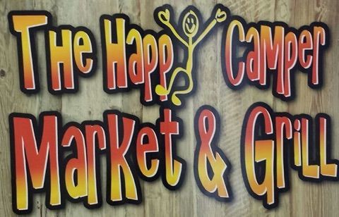 The Happy Camper Market & Grill sign in colorful yellow and red lettering