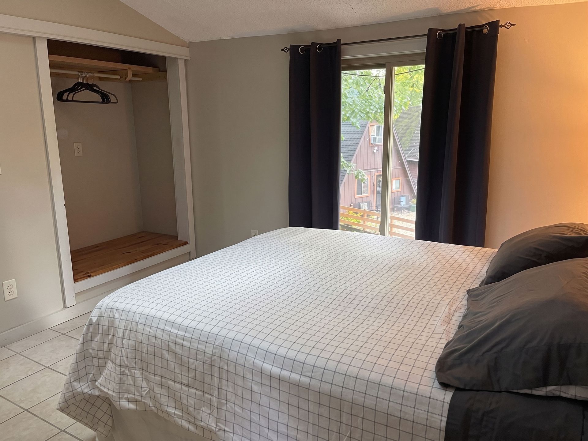 Bedroom with a bed, open closet, and window with dark curtains.