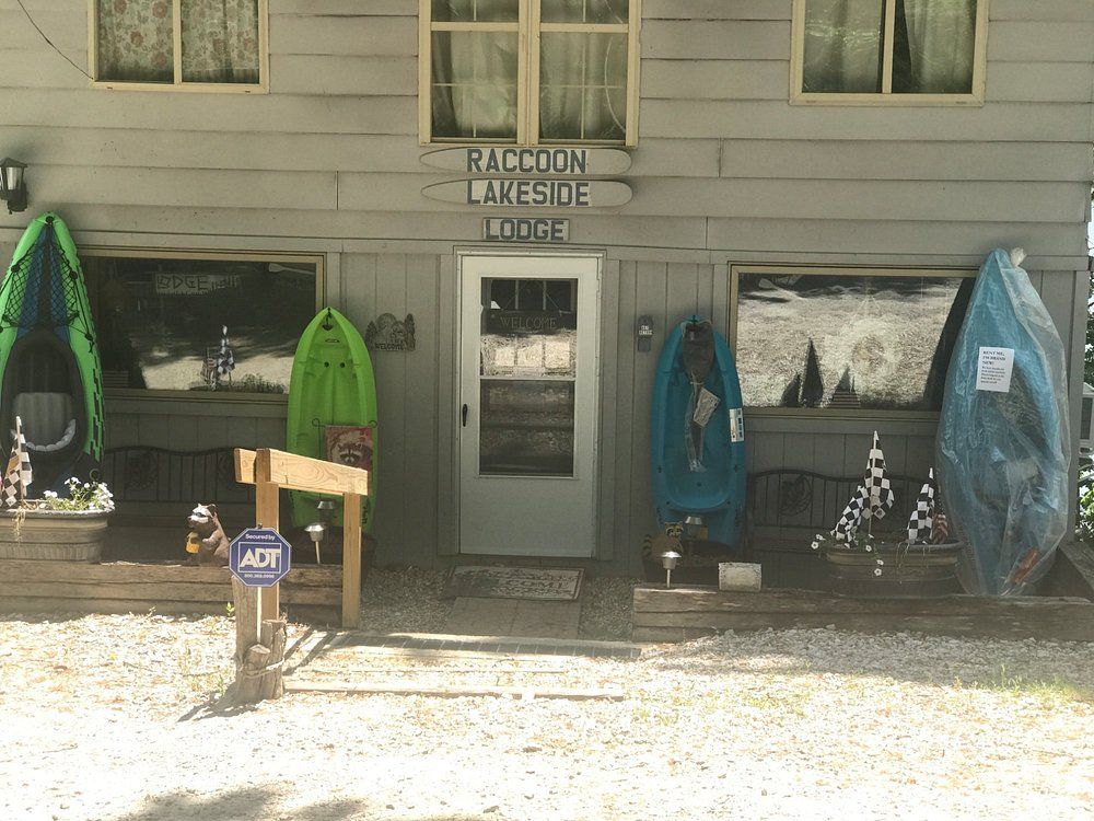 Kayaks and paddleboards stored outside a lakeside building with a central door and sign above it