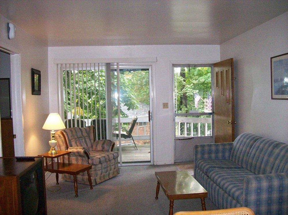 Living room with couch, armchair, lamp, coffee table, and sliding glass doors to a deck