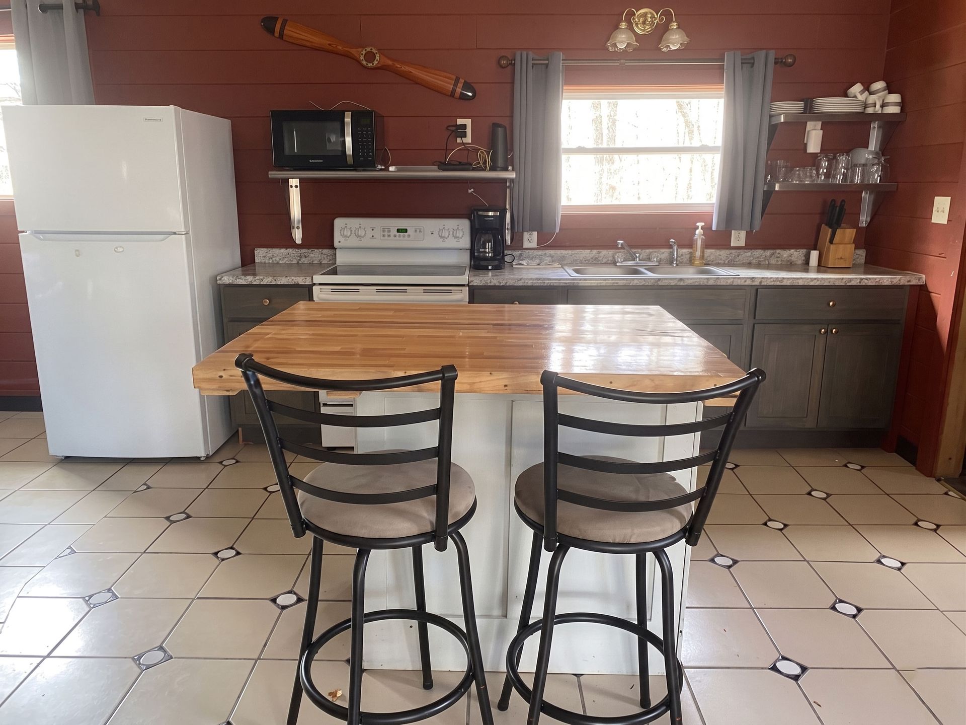 Kitchen with white appliances, red walls, granite counters, and two bar stools at a breakfast counter.