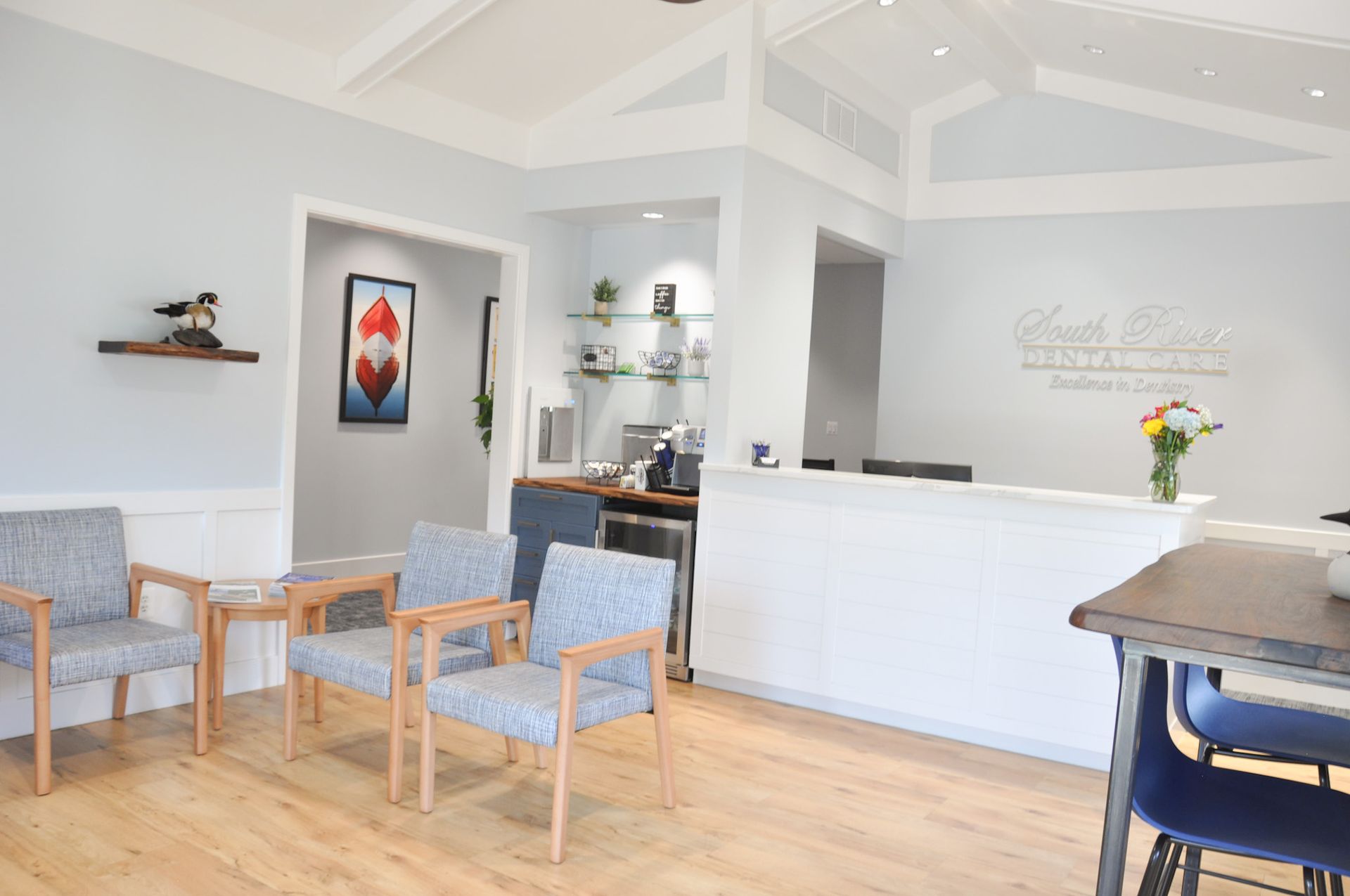 Waiting room with blue chairs, white reception desk, and pale blue walls.