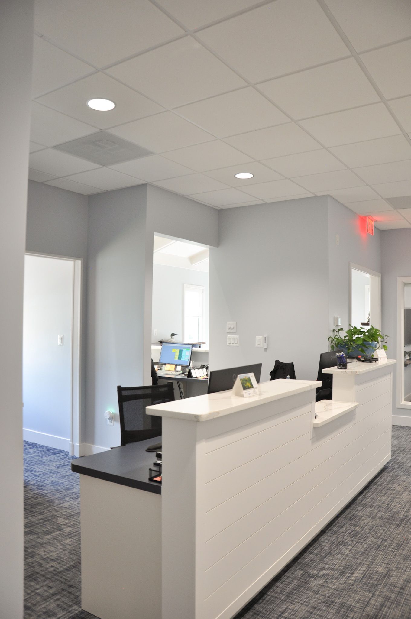 White reception desk in a modern office with gray walls and carpet.