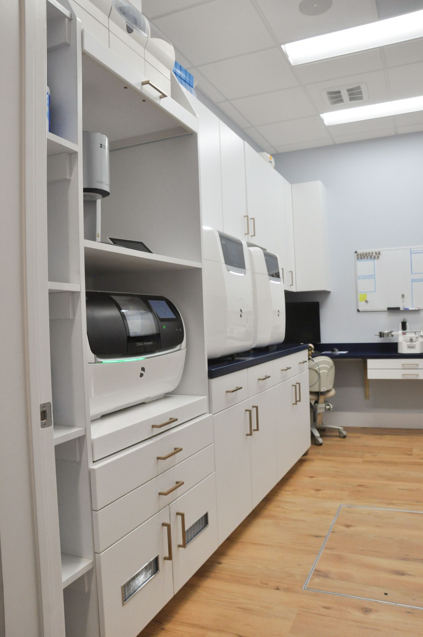 White dental equipment built into white cabinetry in a dental office with wood flooring.