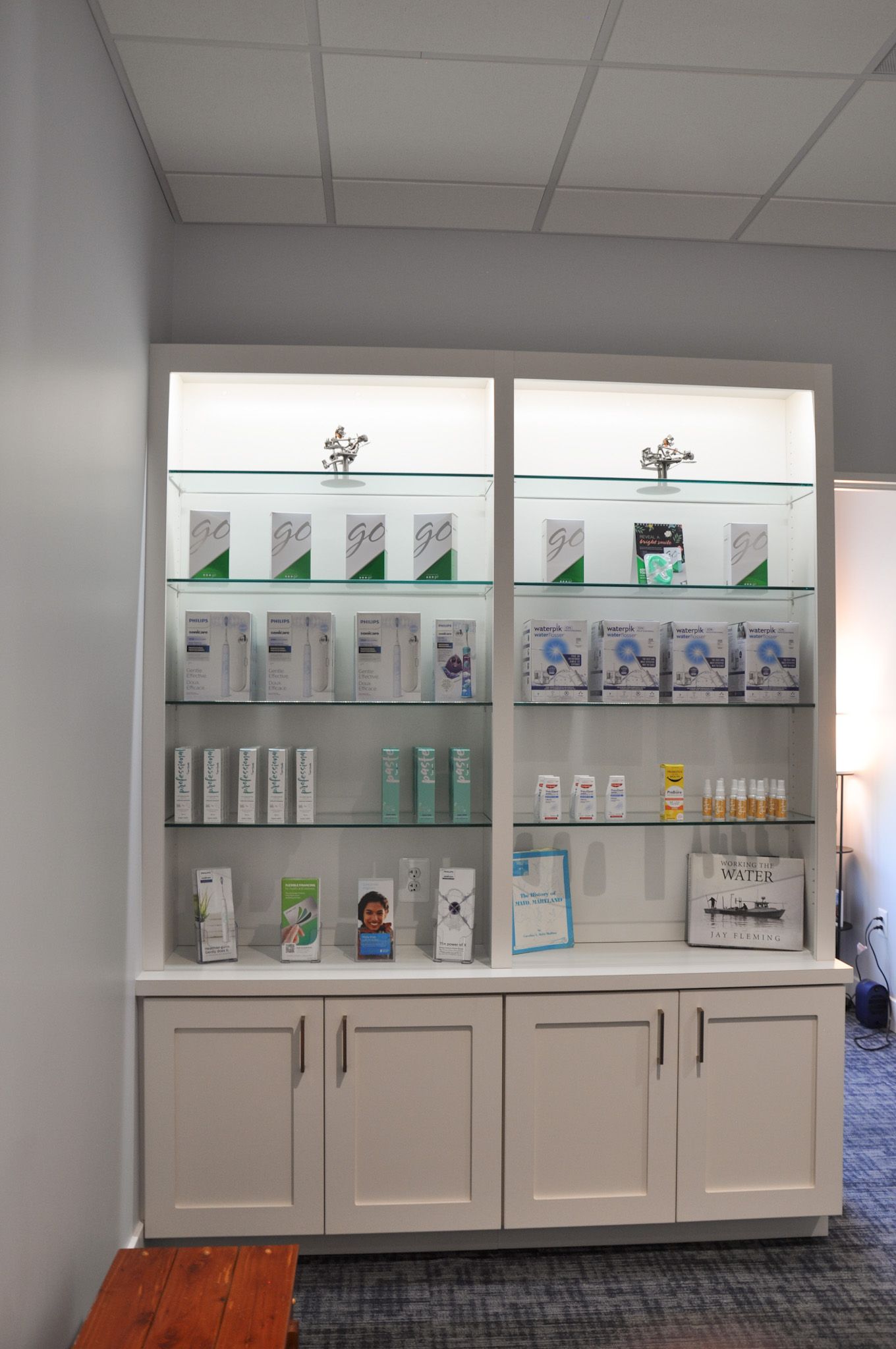 White cabinet with lit shelves displaying product boxes in a store.