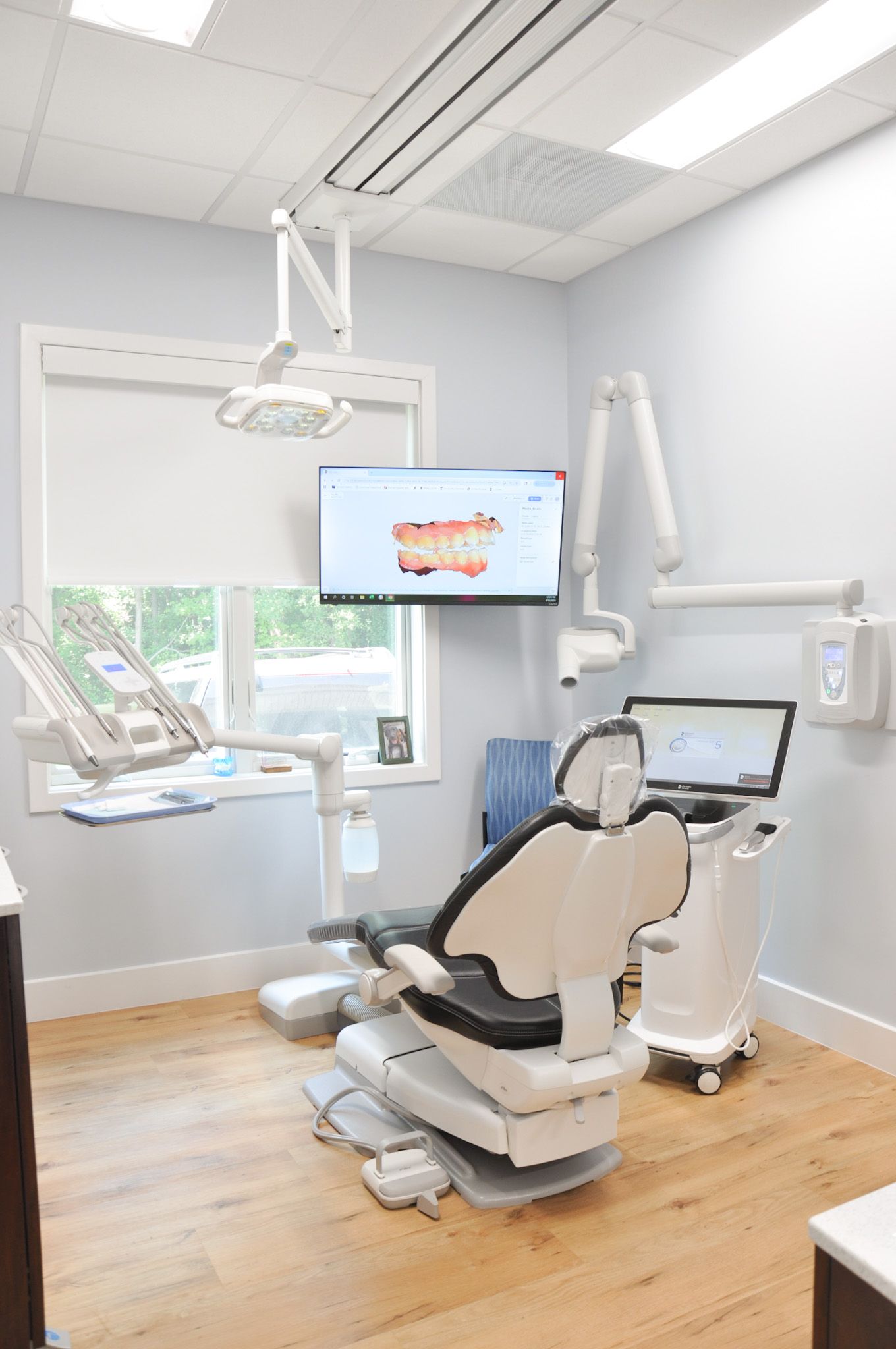 Dental operatory with chair, equipment, and a screen displaying teeth.
