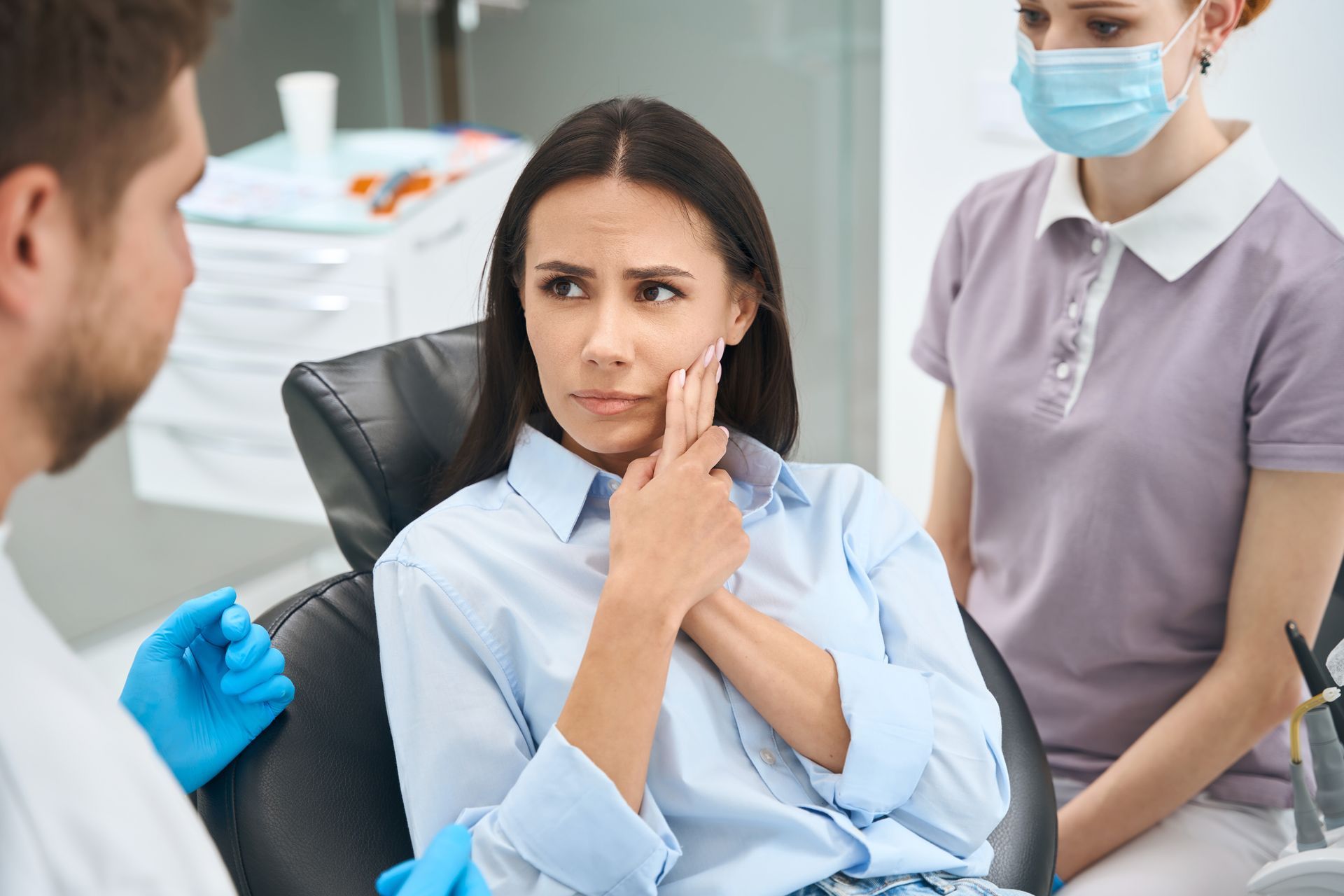 A woman is sitting in a dental chair with a toothache.