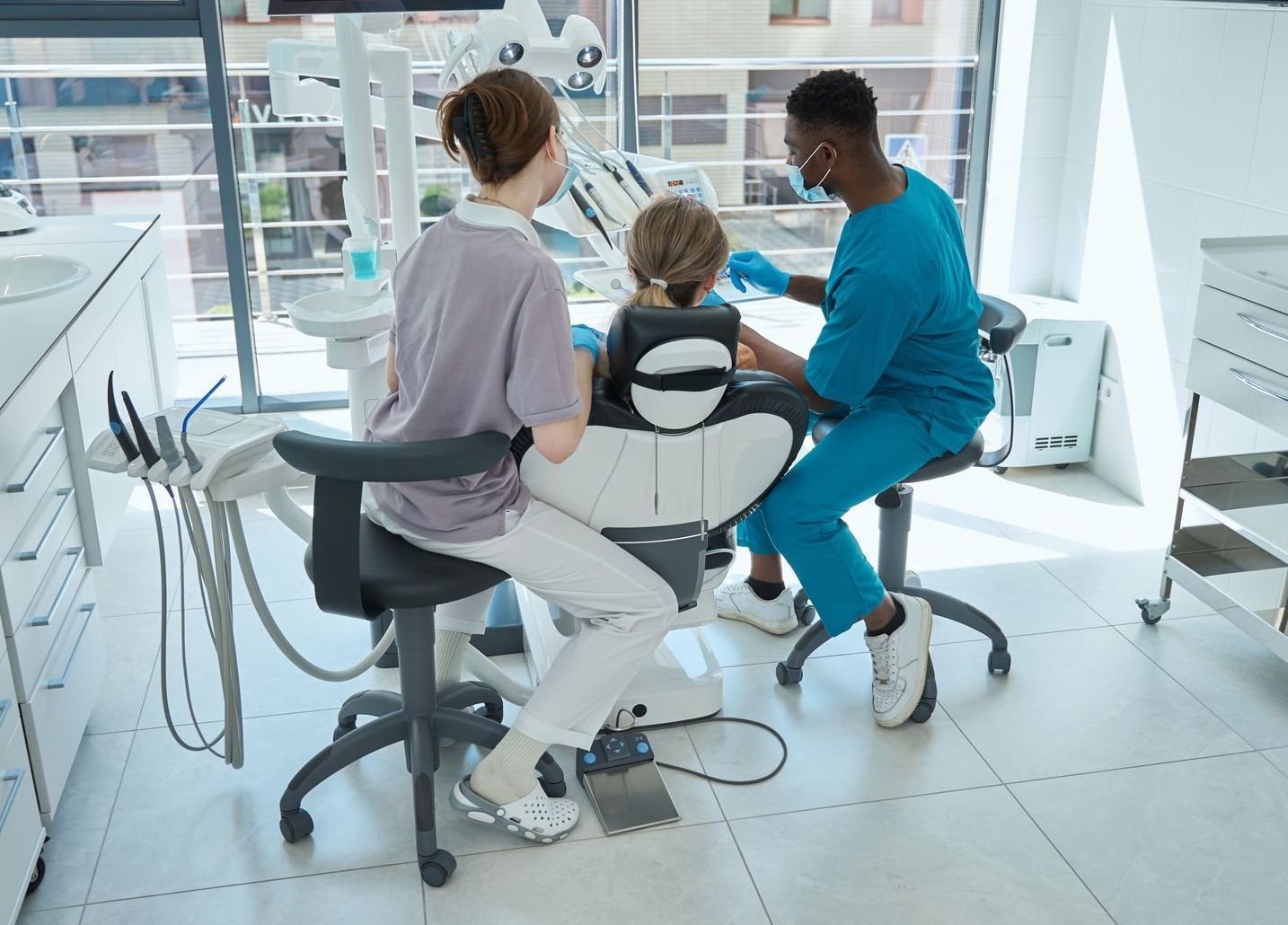 A dentist and a nurse are examining a child 's teeth in a dental office.