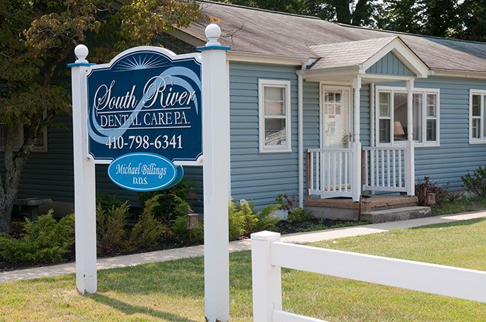 A blue house with a sign in front of it that says south river dental care pa