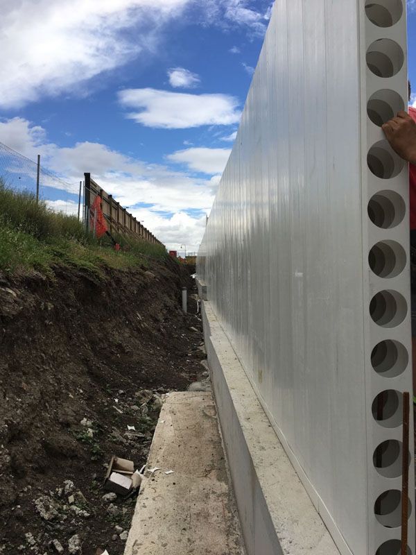 A man is standing next to a large white wall.