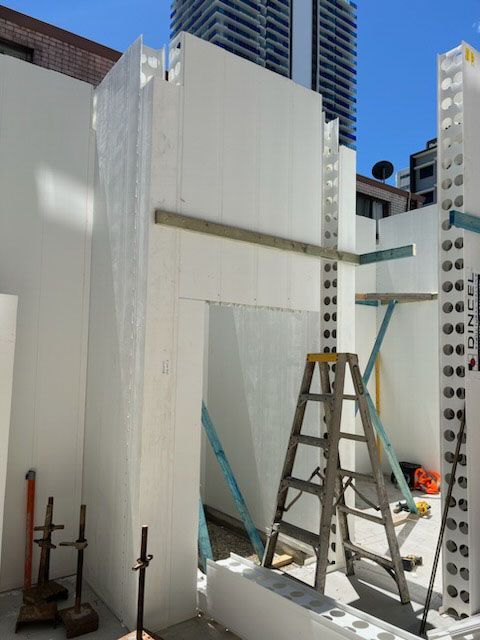 A ladder sits in front of a wall that says dincel