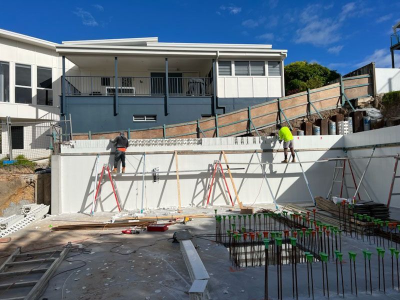 A swimming pool is being built in front of a house.
