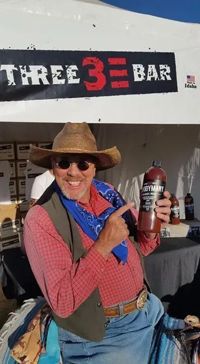 A Man in a Cowboy Hat is Holding a Bottle of Bloody Mary Mix