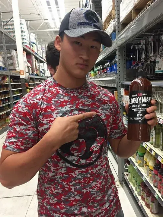 A Young Man is Pointing at a Bottle of Bloody Mary Mix
