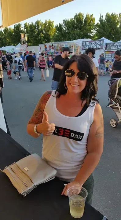 A Woman is Giving a Thumbs Up While Holding a Cup of Beer.
