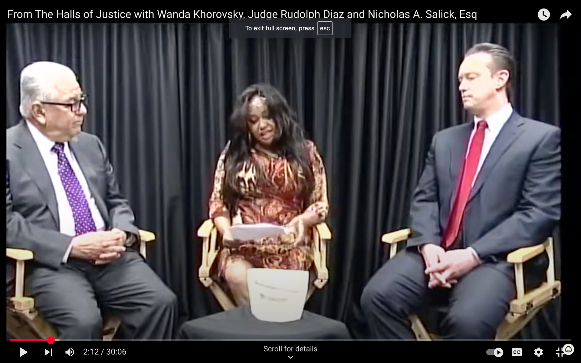 Two men and a woman are sitting in chairs talking to each other.