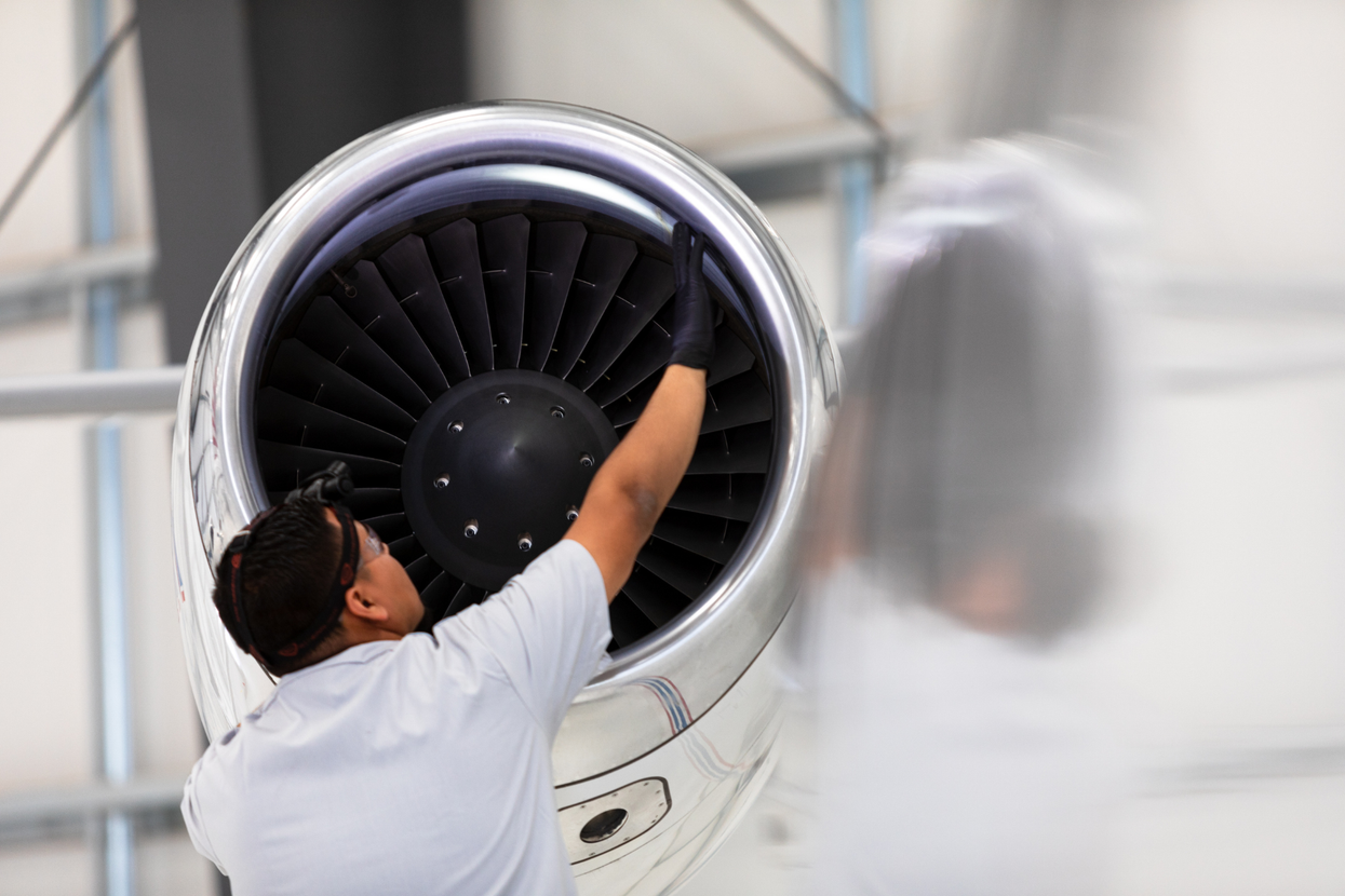 A man is working on an airplane engine in a hangar.