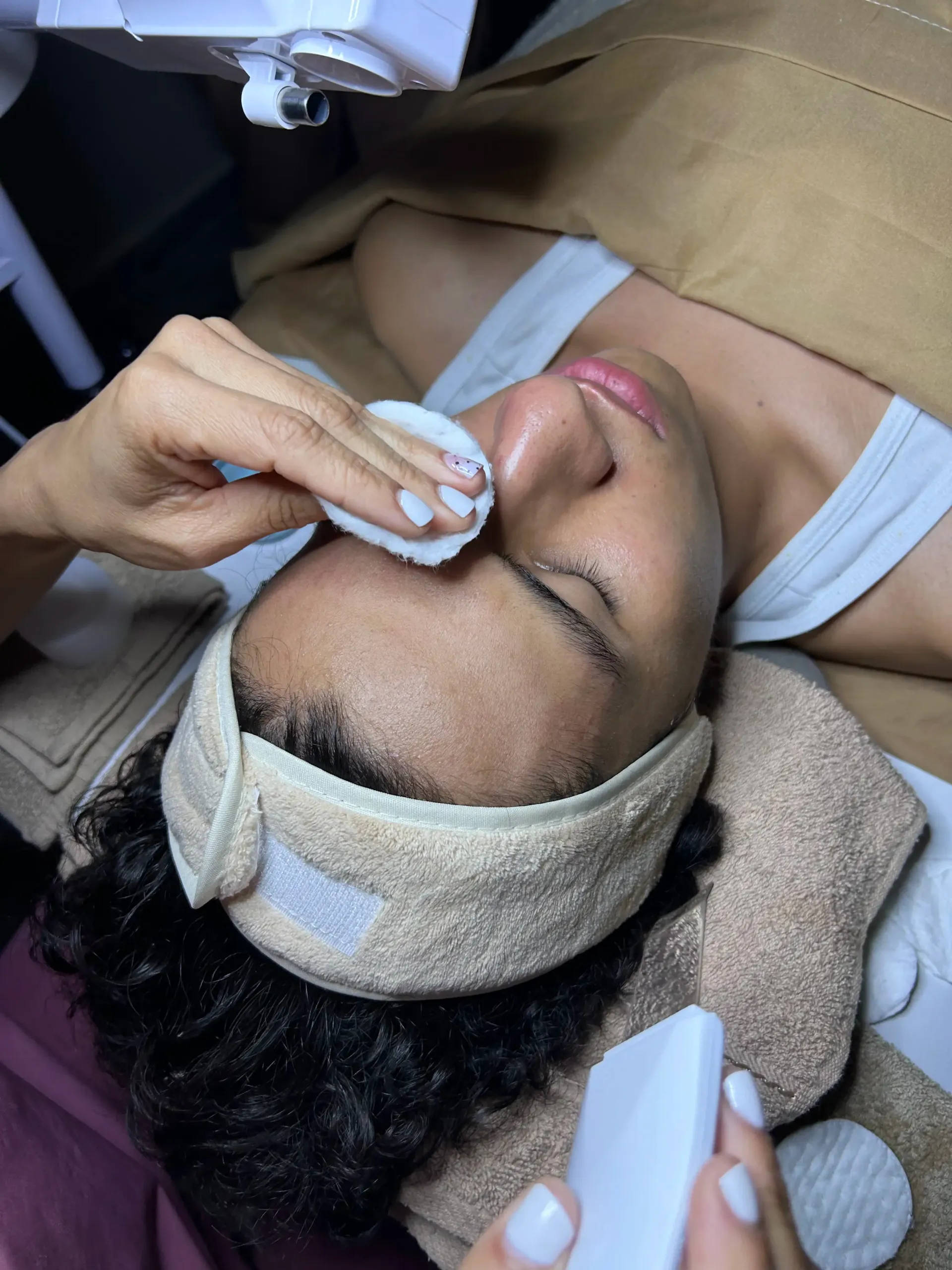 Una mujer está acostada en una cama recibiendo un tratamiento facial.