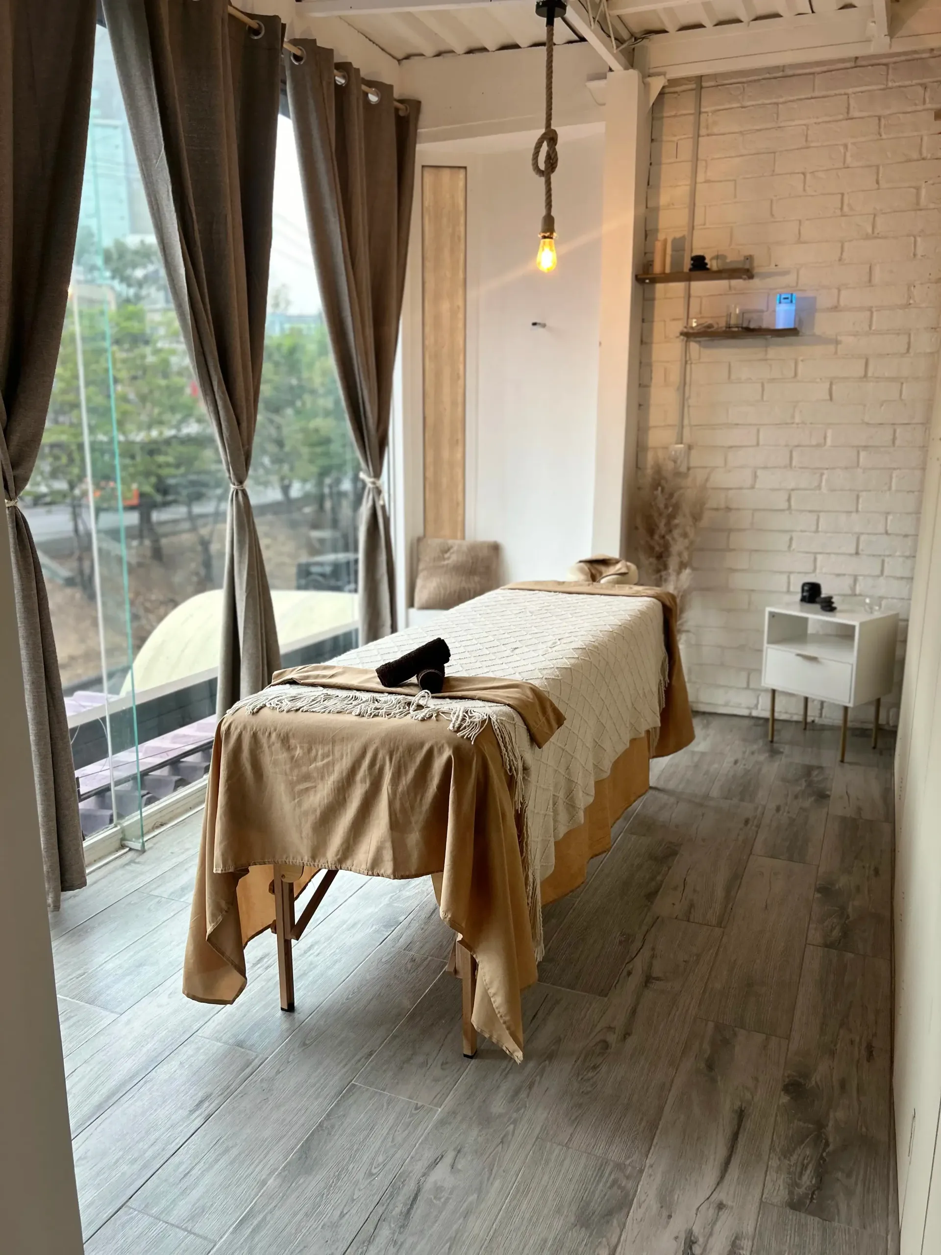 Una camilla de masaje en una habitación con muchas ventanas y cortinas.