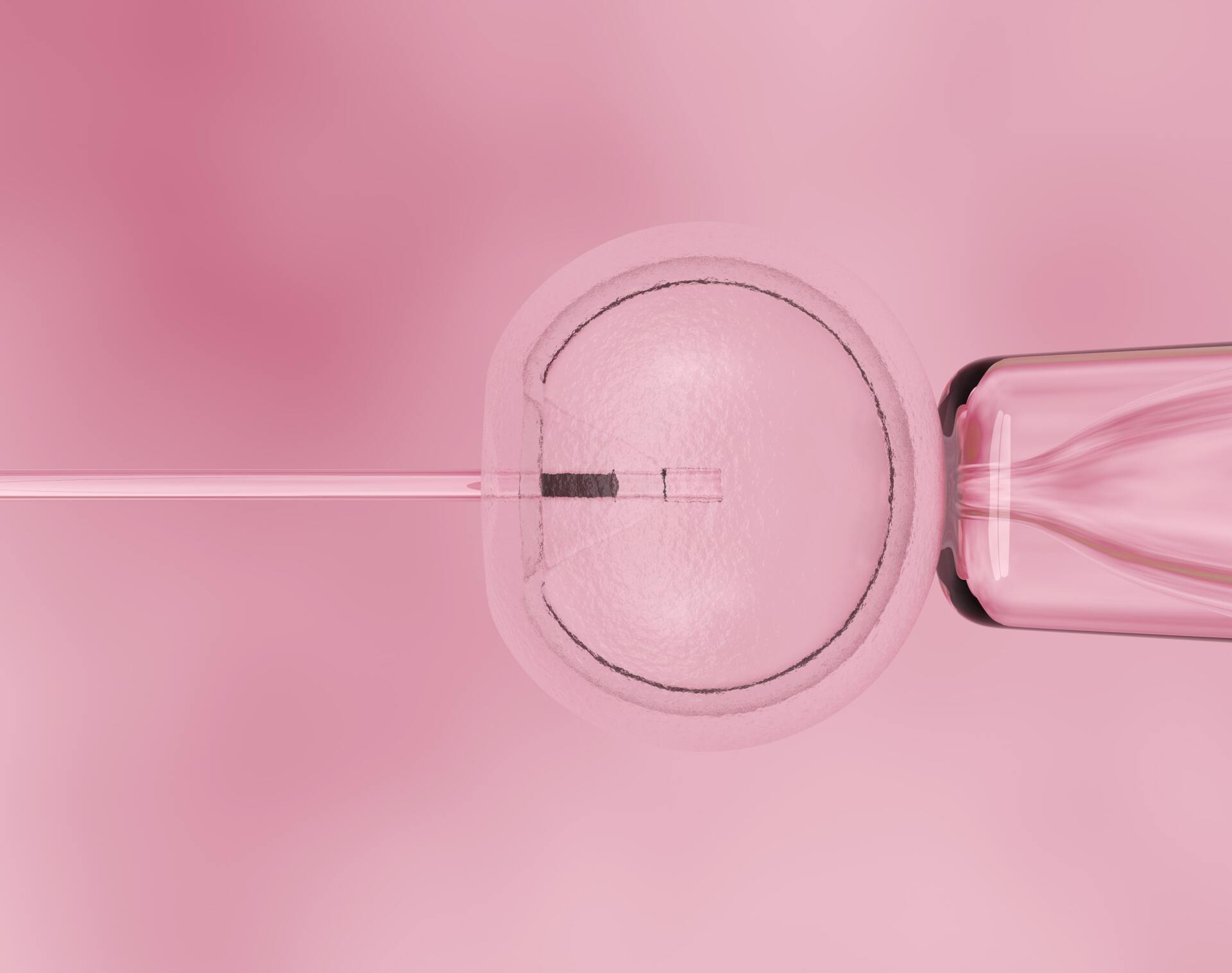 female ivf specialist in white coat and blue gloves sits in front of a microscope and looks at the camera, smiling