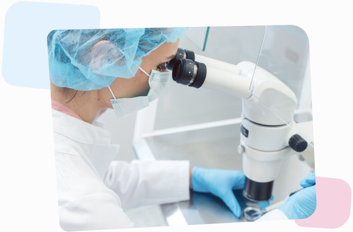 female scientist wearing a hospital mask and bag on her hair, looking through a microscope and putting some substance under its lense