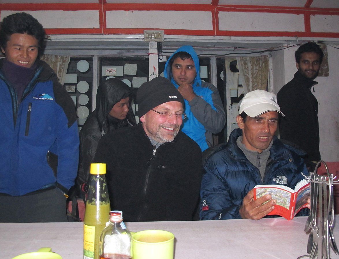 Group of trekkers enjoying a post-dinner gathering in a lodge along the Annapurna Trek in Nepal.