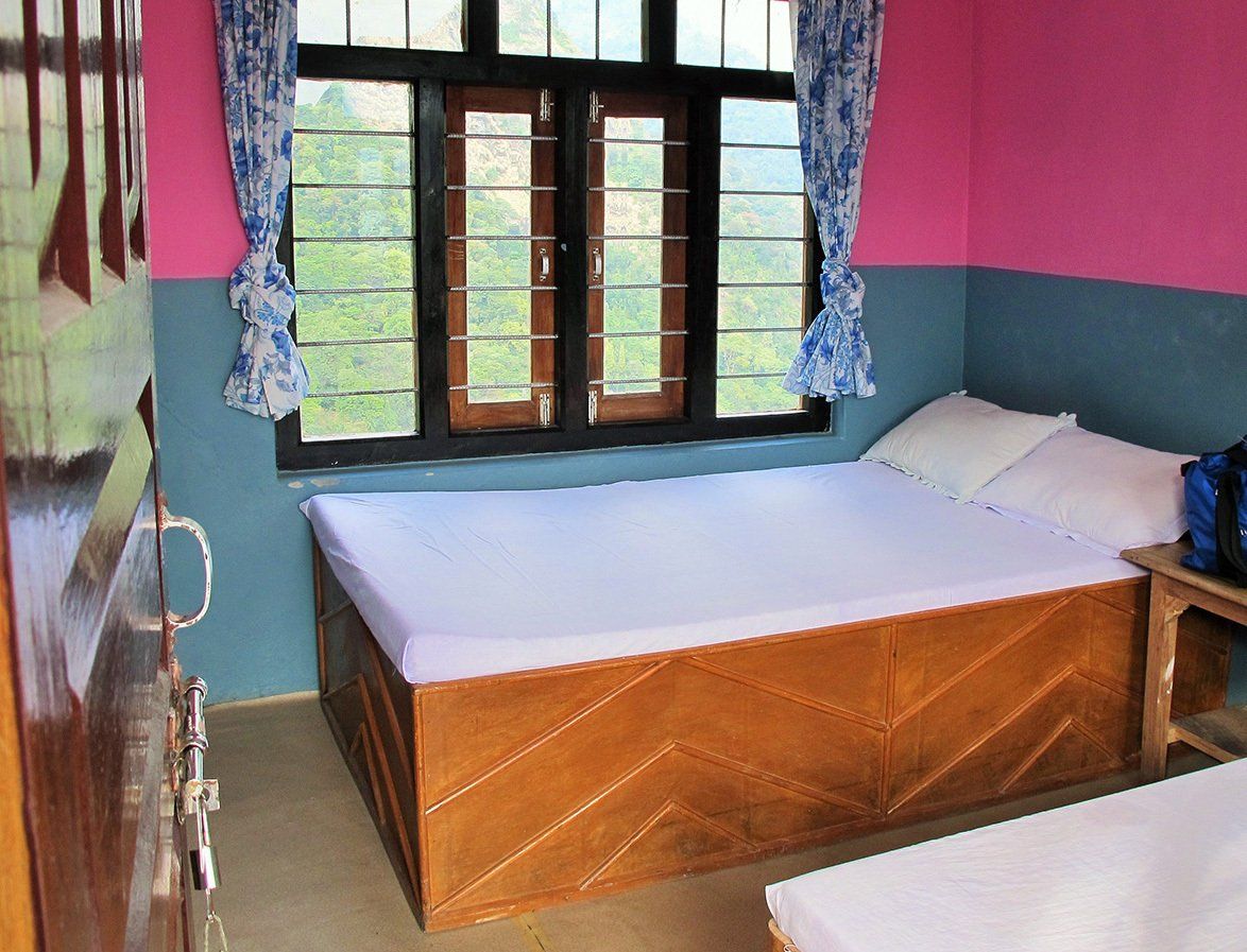 Cozy guesthouse bedroom with scenic mountain views, perfect for trekkers on the Annapurna Trek in Nepal.