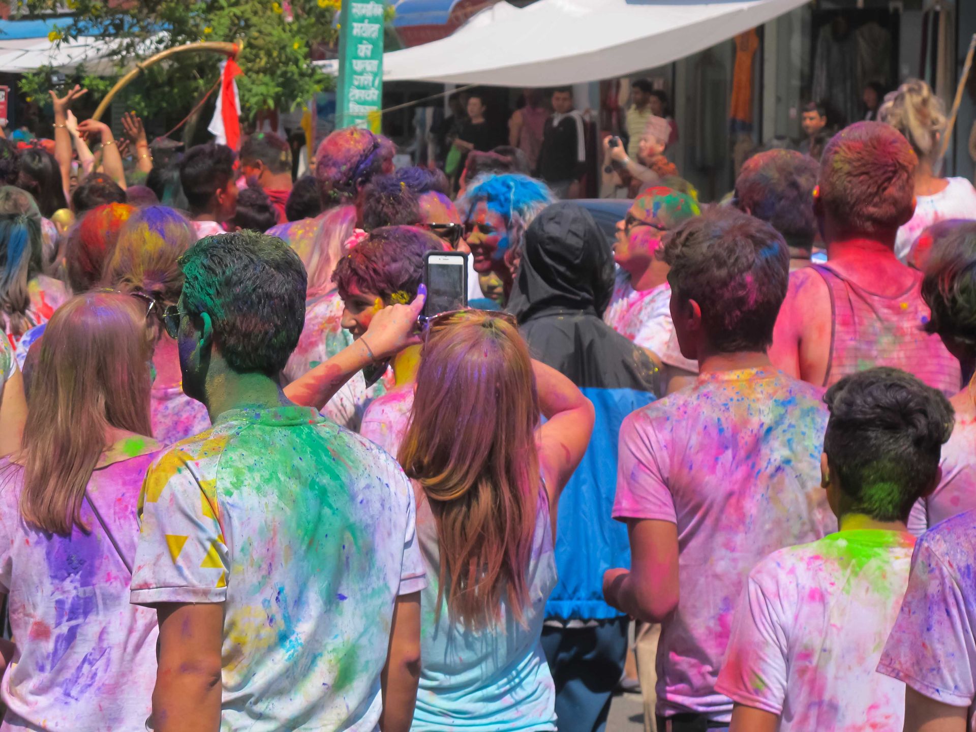 Vibrant scene of people celebrating Holi in Pokhara, Nepal, with colorful powders covering their clothes.