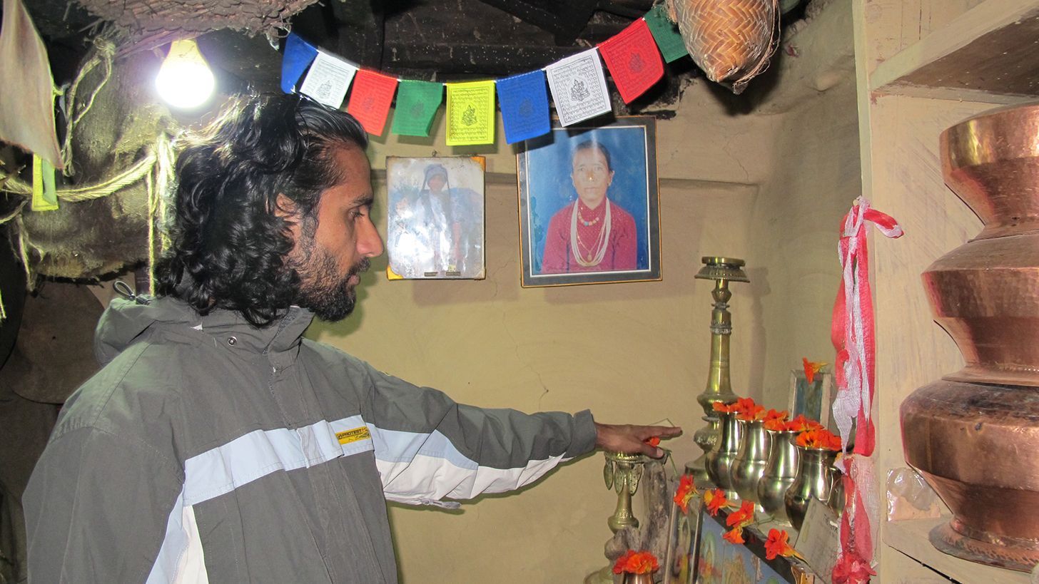 A guide explains local culture inside the Ghandruk Museum, showcasing traditional artifacts and photographs on the wall.