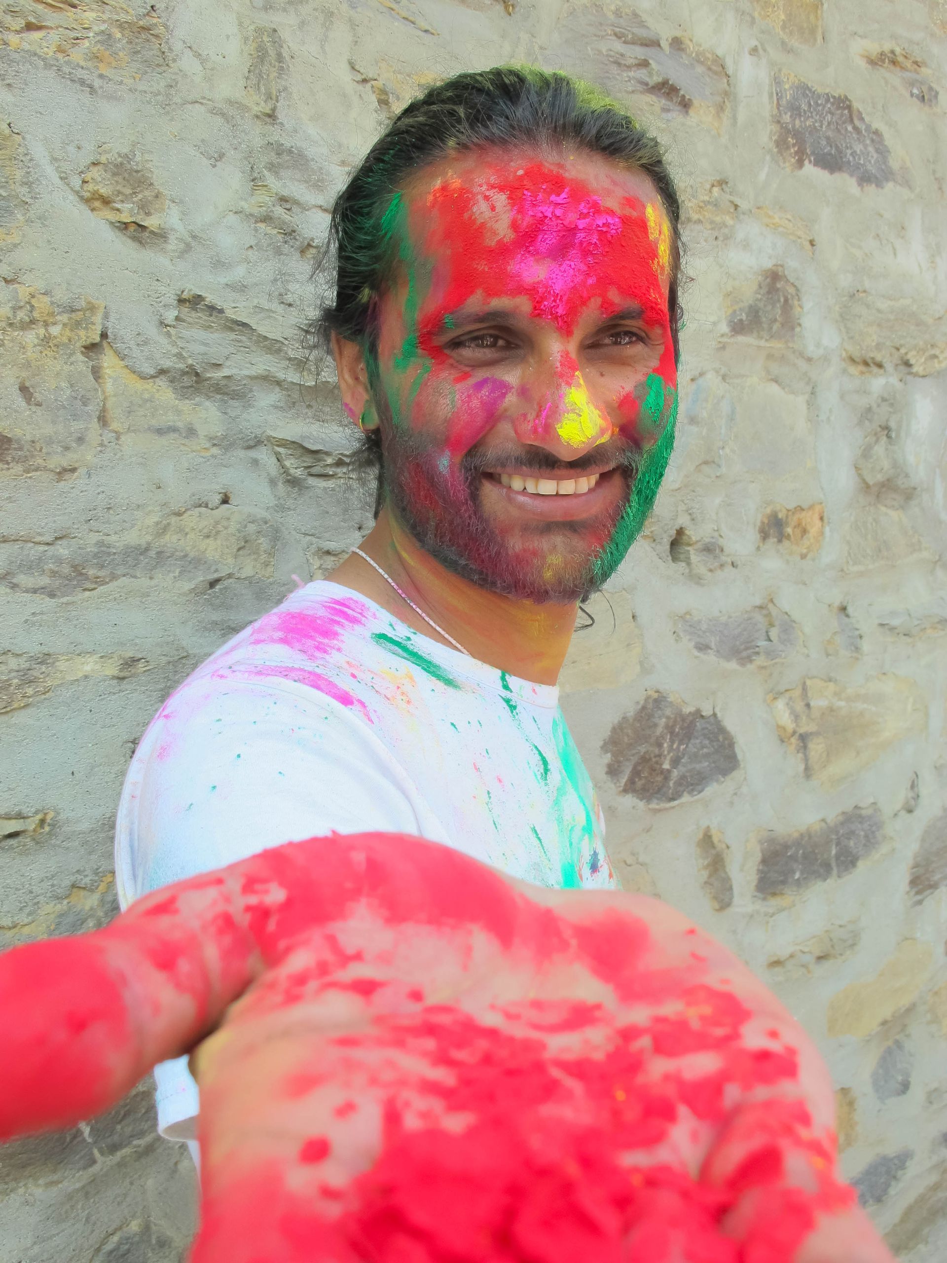 Man with a colorful face during Holi celebration in Pokhara, Nepal, joyfully showcasing the vibrant spirit of the festival
