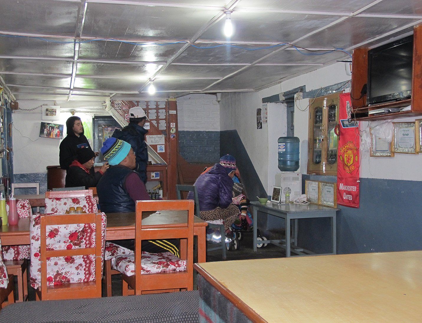 Trekkers gathered in a cozy common room, socializing and warming up after a long day on the Annapurna Trek in Nepal.