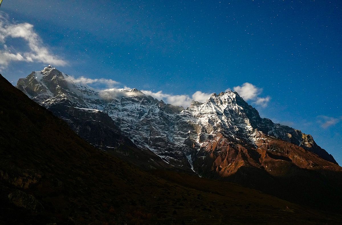 A stunning nightscape of the Nar Phu mountains, illuminated under a star-filled sky, capturing the beauty of the Himalayas.