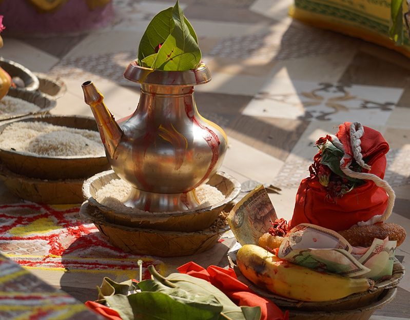 Traditional Nepali puja offerings with a silver pot, rice, fruits, and colorful cloths, used in religious ceremonies.
