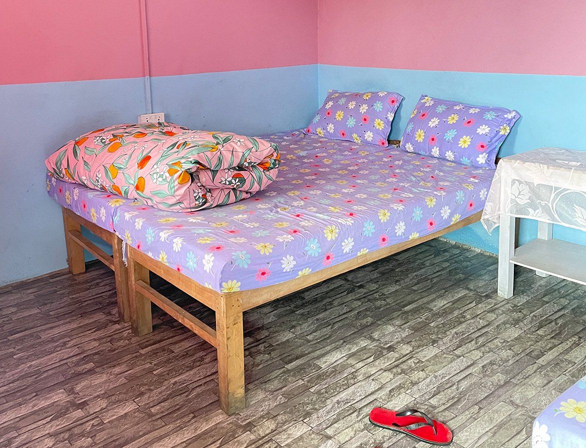Brightly colored bedroom with floral bedding, providing a cheerful resting space on the Annapurna Trek in Nepal.
