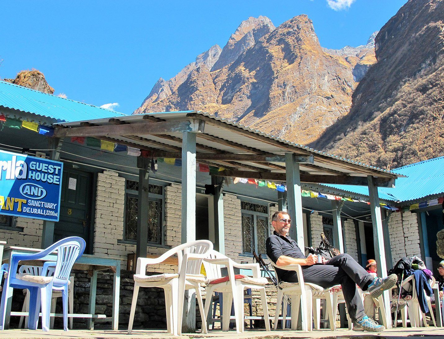 Trekker relaxing at a guest house on the Annapurna Base Camp Trek in Nepal, surrounded by stunning mountain scenery.