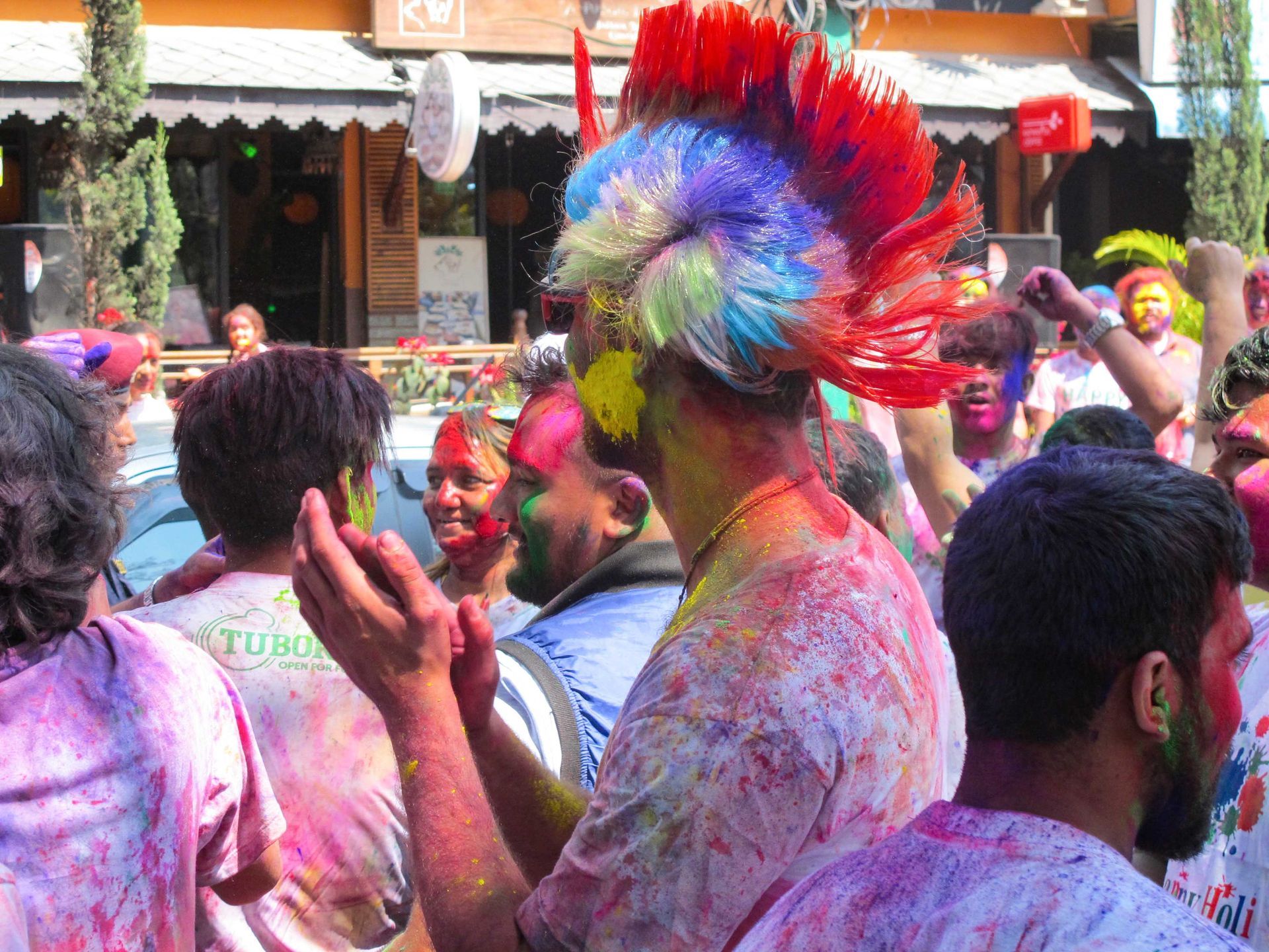 Participants with colorful hair and faces covered in vibrant powders celebrate Holi in Pokhara.