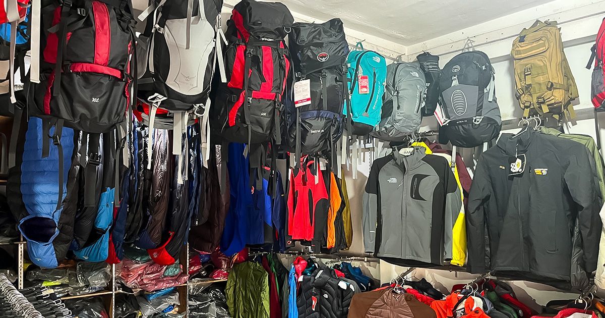 A selection of trekking jackets, backpacks, and outdoor clothing displayed in a shop in Pokhara, Nepal.