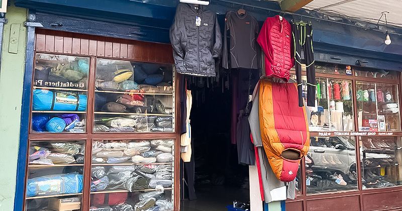 Exterior of a trekking gear shop in Pokhara, Nepal, displaying sleeping bags, jackets, and hiking equipment.